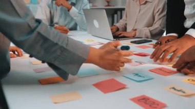 Dinamik takım işbirliği oturumu. Masaya renkli yapışkan notlar düzenleyen, modern ofis ortamında yaratıcılık ve stratejik planlama sergileyen eller. SACTR