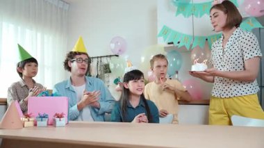 Asyalı kız dilek tutarken ve doğum günü mumu üflerken pasta yiyor. Kafkasyalı anne pasta tutuyor ve enerjik çocuk mum üflerken kızına yerleştiriyor. Güzel bir aile el çırpıyor. Pedagoji.