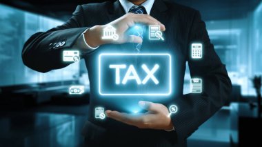Resmi takım elbiseli bir işadamı, modern mali yönetimin altını çizerek finansla ilgili dijital simgelerin arasında parlayan bir vergi levhası gösteriyor. Dörtgen