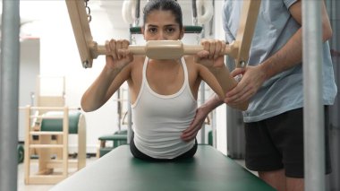 Pilates Cadillac masasında bar tabanlı bir alıştırmada bir müşteriye yardım eden eğitmen. Cadillac 'ta kuğu dalışı yapan kadın beden gücünü ve beden eğitimini arttırıyor. Alışkanlık.