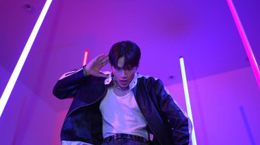 Profesyonel sokak dansçısının sıradan kıyafetlerle kameraya baktığı alçak açılı kamera. Stüdyoda mor ışık altında dururken şehirde pop müzik yapan yetenekli bir sanatçı. Kapatın. Mutluluk.