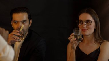 Barmenlerin lüks barında ikram ettikleri portakal dilimli votkayla votka içerek çiftlerle sohbet eden gülümseyen bir müşteri, kulüpteki sosyal hayatın tadını çıkarıyor. Vinosity.