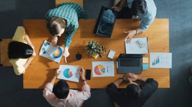 Proje yöneticisinin veri ve mali tabloyu analiz etmek için tablet kullanırken pazarlama ekibinin pazarlama kampanyası ya da toplantı odasında planlama stratejisi üzerinde birlikte çalışmasının en üst görüşü. Cemaat.