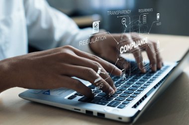 Dijital simgeler ve iş dünyasındaki uygunluğu, düzenlemeyi, şeffaflığı ve gereksinimleri temsil eden metinlerle çevrili bir dizüstü bilgisayarda yazı yazan ellerin yakın görüntüsü. XDMCP