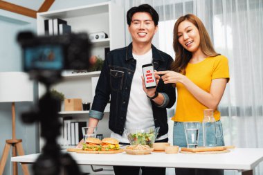 Aşçılar, sosyal medya yemek programı kanalı canlı yayın menü yemeği salatası, kepekli çörek ve video kameradan hamburger kaydı için telefonda yorum okuyorlar. İnfobahn.