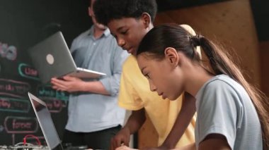 Çeşitli öğrencilerden oluşan bir grup program yazmak için birlikte çalışıyor. Öğretmenler BTMM dersindeki hata noktasını açıklarken çok kültürlü çocukların kodlaması ya da programlaması. Öğretim