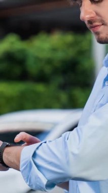 İş adamı, istasyonun otoparkından şarj olurken akıllı telefon hologramındaki EV aküsünün durumunu kontrol ediyor. EV teknolojisi adaptasyonu için temiz enerjinin gelecekteki yaşam tarzı. İnceleyin