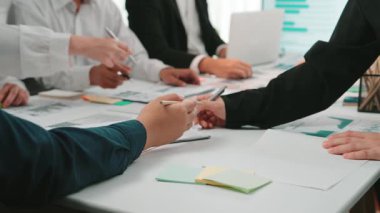 Etkin tartışmalara katılan bir grup profesyonelin masaya çeşitli belge ve çizelgeler sergilendiği dinamik bir ofis toplantısı sahnesi. SACTR