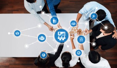 Çeşitli bir ekip, bir yönetim stratejisi toplantısında veri ve çözümleri analiz ederek, anahtar iş kavramları ve hedeflerini gösteren dijital simgelerle işbirliği yapıyor. Dostluk