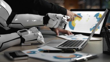 Robot kolla işbirliği yapan, dijital tasarımları ve dizüstü bilgisayardaki yaratıcı kavramları analiz eden, yenilik ve takım çalışmasını vurgulayan gelecekçi bir çalışma alanı. Noogenesis