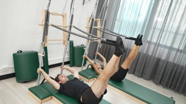 Bir grup müşteri, çekirdek dayanıklılığını ve bacak bağını geliştirmek için Cadillac reformatör makinesinde pilates egzersizleri yapıyor. Sağlıklı müşterilerin daha düşük poz verip kaldırma pozlarının üst görüntüsü. Sağlıklılık. Alışkanlık.