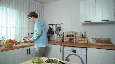 Mutlu baba yemek pişirirken müziğe geçiyor ve modern mutfakta öğle yemeği hazırlıyor. Aktif baba, sebze ve mutfak gereçleri ile çevrili sağlıklı yemek ya da salata yaparken şarkıyla dans ediyor. Pedagoji.