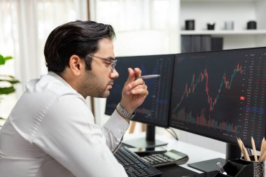 Akıllı tüccar işadamı, modern merkez ofisindeki araştırma pazarında en yüksek kârlı finansal teknolojiye yatırım yaparak bilgisayar üzerinde iki dinamik borsa yatırım ekranını analiz ediyor. Tahmin et..