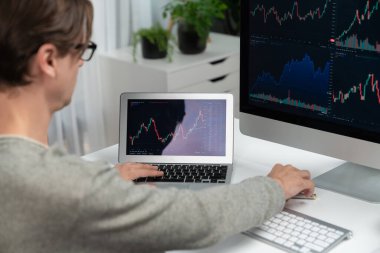 Bilgisayar ve dizüstü bilgisayarı kullanarak, çalışma masasındaki dinamik artırılmış borsa grafiğinin en yüksek kar değerini araştıran bir tüccar, modern ofisteki ekrandaki döviz kuru değerini analiz ediyor. Bireysel.