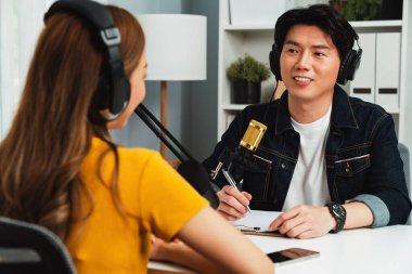 Gülümseyen radyo etkili sunucusu kulaklık takıyor kadın konuşmacı ile röportaj yapıyor sosyal medya internet sitesinden dinleyicilere bilgi paylaşıyor stüdyo kaydında sabah canlı yayın kanalı. İnfobahn.