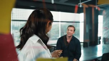 Genç kendine güvenen iş kadını projeyi uzman yatırımcıya sundu. Profesyonel proje yöneticisi başlangıç projesini açıklamak için yapışkan notlar kullanır, beyin fırtınası fikirlerini yatırımcıya paylaşır. Yönlendirici.