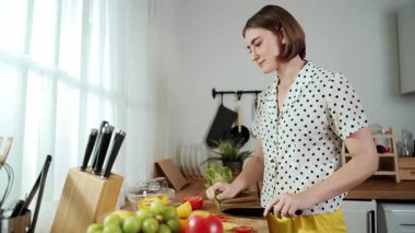Kafkaseli anne kahvaltıda sebze pişirirken mutlu anne de modern mutfakta salata için taze malzemeler hazırlıyor. Hizmetçi sağlıklı yemek pişiriyor. Dikkat konsepti. Pedagoji.