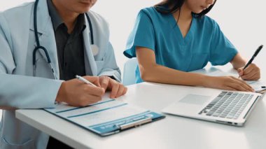 Hastane masasında birlikte çalışan ve tıbbi tedavi planlayan çeşitli profesyonel sağlık görevlileri. Takım çalışması başarılı hastalıklara ve hastalıklara yol açar. Ağır çekim. Katı.