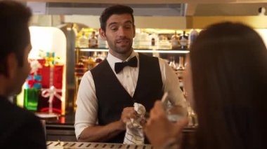 Lüks tezgah barında müşteri çiftiyle konuşurken bardakları silip gülen zeki barmenler, canlı bir gece partisi atmosfer gece kulübünde özel içecekler hazırlıyorlar. Vinosity.