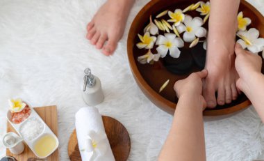 Kadınlar lüks spa salonlarında keyifli ayak masajlarına devam ederken, masör de hafif gün ışığı atmosferinde refleksoloji terapisi veya otel ayak spa 'sında. Sessiz.