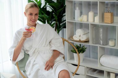 Güzellik ya da vücut bakımı güzellik salonu yaşam tarzı konsepti. Bornoz giyen bir kadın lüks otel kaplıcalarında ya da tatil odasında içkiyle rahatlıyor. Tatil ve boş zaman rahatlığı. Sessiz.