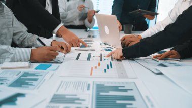 Çizelge ve grafiklerin ayrıntılı analizinde yer alan, işbirliğini ve stratejik planlamayı vurgulayan dinamik bir iş toplantısı sahnesi. SACTR