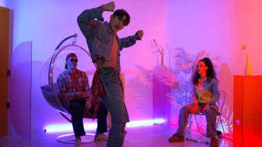 Çok kültürlü bir arkadaş kürsüde otururken Asyalı yetenekli bir dansçı modern müziğe geçiyor. Profesyonel dansçı, hipster takımı tezahürat yaparken ve desteklerken enerjik adımlar atıyor. Mutluluk.