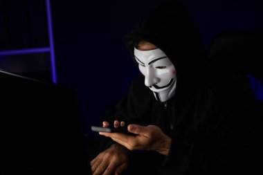 Beyaz gülümseyen isimsiz suçlu maskesi kurbana sesleniyor, kişisel bilgileri hacklemeye ikna ediyor, veri sunucu sistemindeki bilgisayar korsanlarının kullandığı şifreleme programını paylaşıyor. Tahmin et..