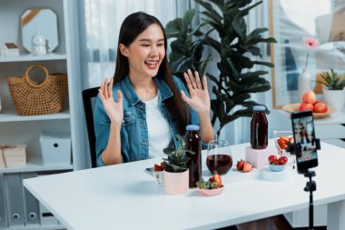 Gülümseyen, güzel Asyalı genç, lezzetli karışık çilek ve kiraz suyu detoksu içeceklerini inceleyen, sosyal medyada özel promosyon satışı için sağlıklı ürünler sergileyen. Taktik.