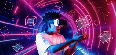 VR gözlük takan zeki bir genç ve geometrik şekil konusunda heyecanlı. Afrikalı oyuncu gündelik kıyafet giyiyor ve artırılmış gerçeklik teknolojisi kullanırken parlak ışık rengiyle çevrili. Yaratıcılık.