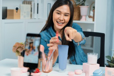Genç, güzel Asyalı kozmetik makyaj ruju matte pastel rengini modern odadaki sosyal medyada kol testi tanıtımında en çok satanlar listesinde gösteriyor. Taktik.