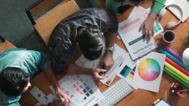 Tasarımcı fikirleri yazarken proje yöneticisinin yukarıdan aşağıya bakan görüntüsü. Akıllı iş adamları logo tasarımı fikrini açıklarken tasarımcılar palete bakarken temayı seçiyorlar. Sempozyum.