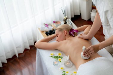 Sıcak bitkisel top spa masaj vücut tedavisi, masör kadın vücuduna nazikçe şifalı bitki torbası bastırıyor. Aromaterapi dinlenme sükuneti ve sükuneti kaplıca salonundaki atmosferi aydınlatıyor. Sessiz.