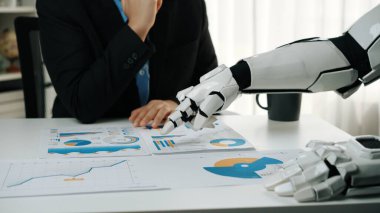 Bir insan figürü, veri analizi ve karar verme konusunda teknoloji ve insan uzmanlığı arasındaki etkileşimi vurgulamak için robotik bir kolla iş tartışmasına girer.