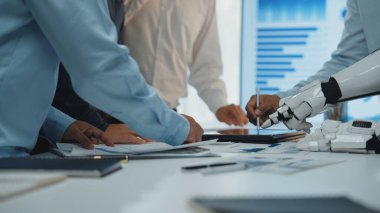 Modern ofis ortamında üretkenliği ve yeniliği artırmak için insan ekibinin robot koluyla etkileşime girdiği ortak bir toplantıyı gösteren dinamik bir sahne.