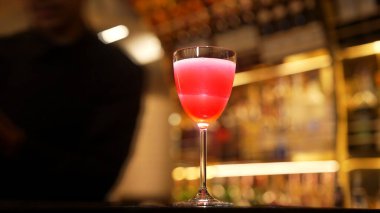 Gülümseyen Asyalı akıllı barmen, lüks tezgah barında bardakla karışık kokteyl hazırlıyor, VIP müşteriyle birlikte gece hayatı sıcak gece kulübü servisinde özel bir içecek hazırlıyor. Vinosity.