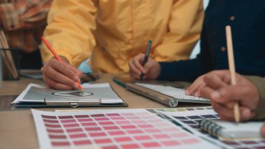 Çeşitli profesyonellerden oluşan bir ekip, modern ofis ortamında renk örnekleri ve çizimler kullanarak yaratıcılık ve takım çalışması sergileyen bir tasarım projesi üzerinde aktif olarak işbirliği yapmaktadır. SACTR