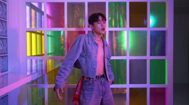 Kameraya bakarken kollarını esneten seksi kıyafetli Asyalı dansçı. Profesyonel sanatçı gece kulübünde renkli neon ışıkları canlı bir şekilde dururken serbest stil dansı yapıyor. Mutluluk.