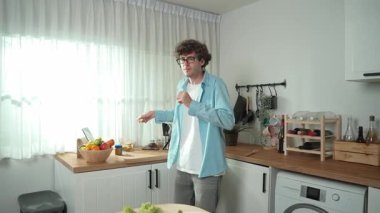 Mutlu baba yemek pişirirken müziğe geçiyor ve modern mutfakta öğle yemeği hazırlıyor. Aktif baba, sebze ve mutfak gereçleri ile çevrili sağlıklı yemek ya da salata yaparken şarkıyla dans ediyor. Pedagoji.