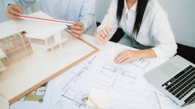 Profesyonel mühendis ev modelini tartartarken, yetenekli tasarımcı da planına yazar. Birlikte çalışmak, işbirliği, işbirliği. Yaratıcı tasarım ve takım çalışması konsepti. - Yakın çekim. Tertemiz.