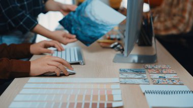 Bilgisayar üzerinde çalışırken renk paletleri ve sanat eserleri seçen, ilham ve işbirliğini somutlaştıran tasarımcıların ellerini gösteren canlı bir yaratıcı çalışma alanı. SACTR