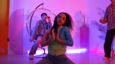 Çekici mutlu dansçı kameraya bakarken zeki kadın neon ışıkla kafiyeli hareket ediyor. Profesyonel İspanyol şarkıcı çeşitli arkadaşlarıyla renkli kıyafetler giyerken break dans yapıyor. Mutluluk.