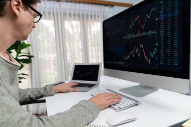 Bilgisayar ve dizüstü bilgisayarı kullanarak, çalışma masasındaki dinamik artırılmış borsa grafiğinin en yüksek kar değerini araştıran bir tüccar, modern ofisteki ekrandaki döviz kuru değerini analiz ediyor. Bireysel.