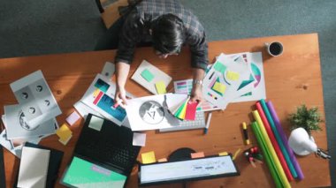 Akıllı iş adamının logo grafiği tasarlarken renk paletleri seçmesinin üst görünümü. Profesyonel iç mimar tasarımının hava görünümü ve renk paletleri kullanarak renk temasını seçin. Sempozyum.