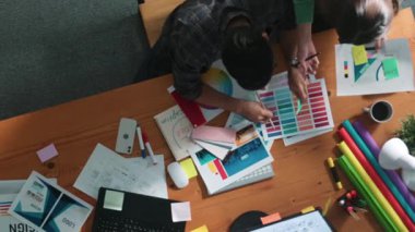 Tasarımcı yazma fikri ekrana bakarken proje yöneticisinin üst görünümü. Akıllı iş adamlarını kapat ve tasarımcı palete bakarken logo tasarımı fikrini açıkla. Sempozyum.