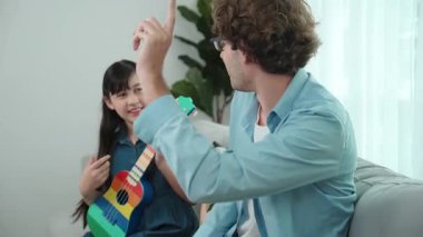 Akıllı kız oturma odasında ukulele çalarken beyaz bir babanın motivasyona ve teşviğe el çırpması. Amerikalı kız babasına gösterirken gitar öğreniyor. Aile yaratma kavramı. Pedagoji..