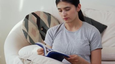 Kanepede oturan orta yaşlı bir kadın, sosyal ve teknolojik mesleki gelişmeler hakkında ders kitabı okur ya da zeki bir anne olmak için çocuk yetiştirir. Hayat boyu öğrenme konsepti. Uyumsuzluk.