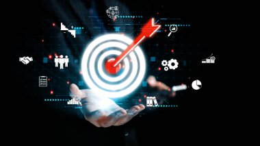 Bu görüntü, analitik, büyüme ve karanlık bir zemin karşısında işbirliğini vurgulayan dijital unsurlarla iş dünyasındaki hedef başarı kavramını temsil etmektedir. Dörtgen