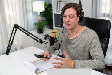 Sunucu kanalı, gülümseyen akıllı yayıncı kaydı, senaryosu ve akıllı telefonuyla sosyal medyada sohbet programı, kulaklık takarak modern ev stüdyosundaki video flamalarını kaydediyor. Bireysel.