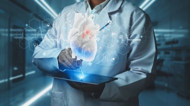 Doktorun tableti tutmasına ve laboratuvarda bulanık bir geçmişi olan kalp hologramıyla kalemi işaret etmesine yakın durun. Sağlık çalışanı semptomları kontrol edip kalp ameliyatına hazırlanıyor. Teknoloji. İyileştirici.